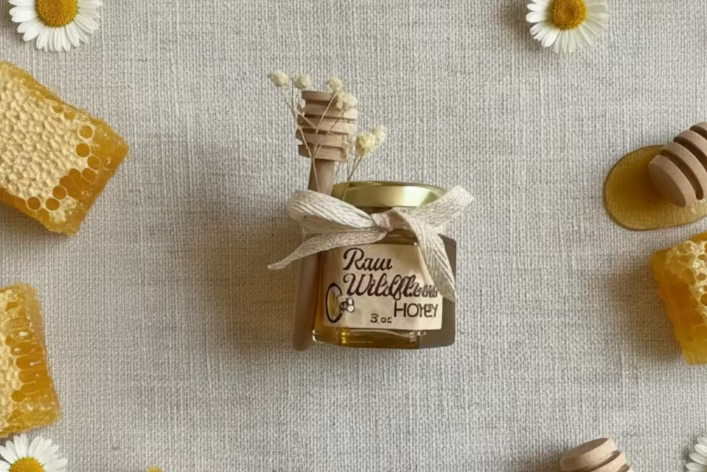 Small jar of honey with a decorative straw on a textured gray background