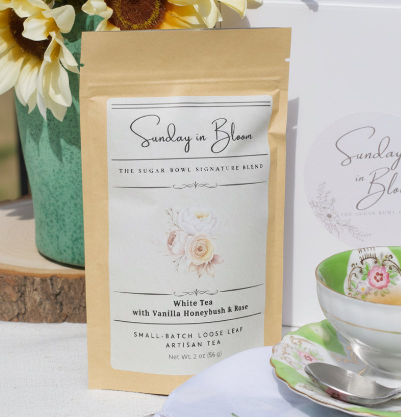 Tea package labeled 'Sunday in Bloom' with a teacup and floral elements on a table.
